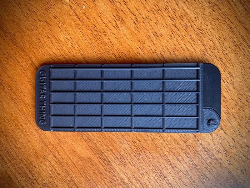 Guitar Thing closed, seen from above on a wooden table, showing its fret and string grid